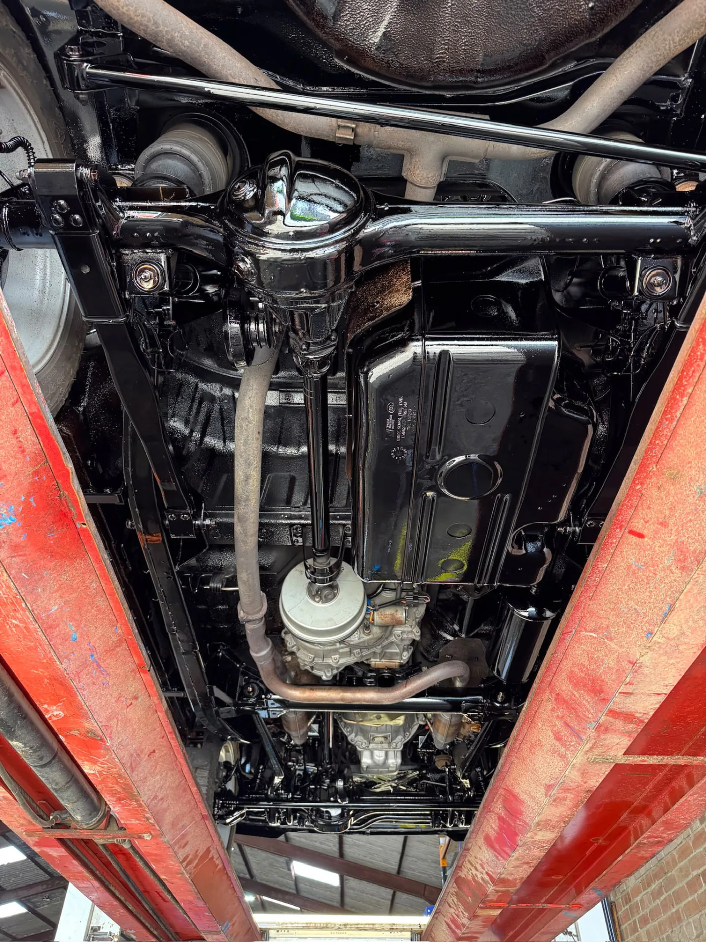 Restored black vehicle underbody, drivetrain and suspension on a workshop lift