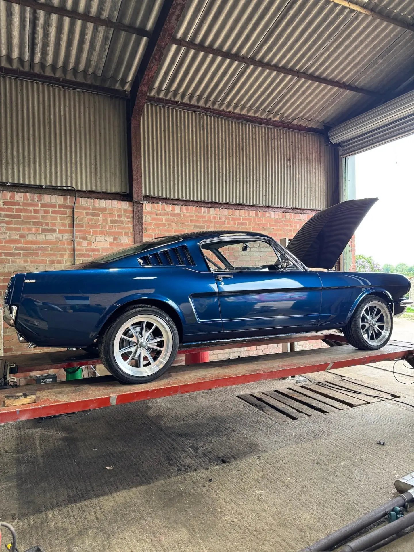 Blue classic Ford Mustang fastback on a workshop lift