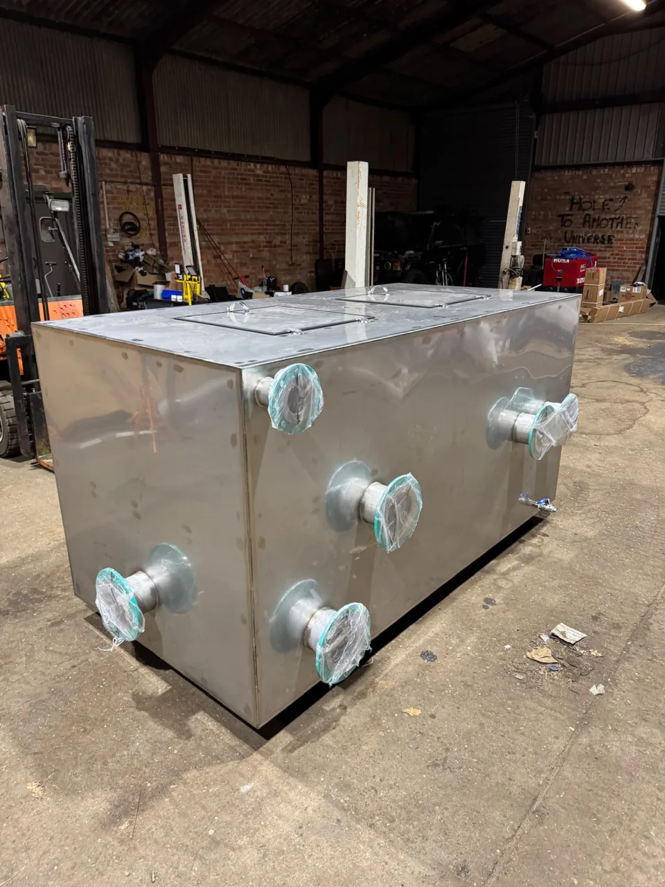 Fabricated rectangular stainless tank with flanged connections inside the workshop