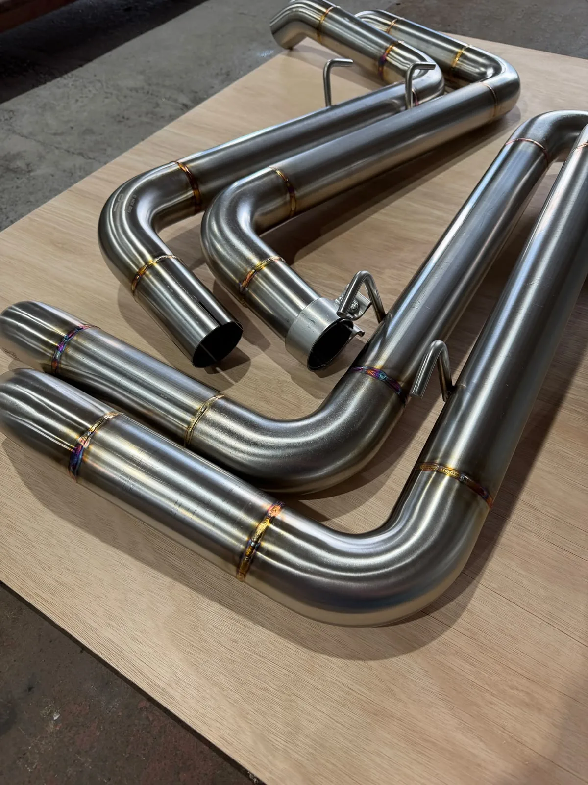 Fabricated stainless exhaust pipes and silencers arranged on a workbench