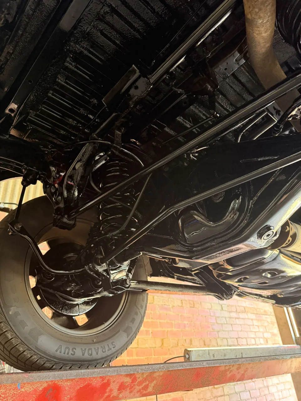 Black coated chassis and rear suspension beneath a vehicle