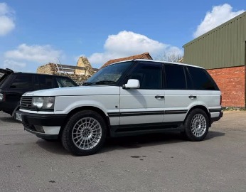 White Range Rover parked outside a brick workshop