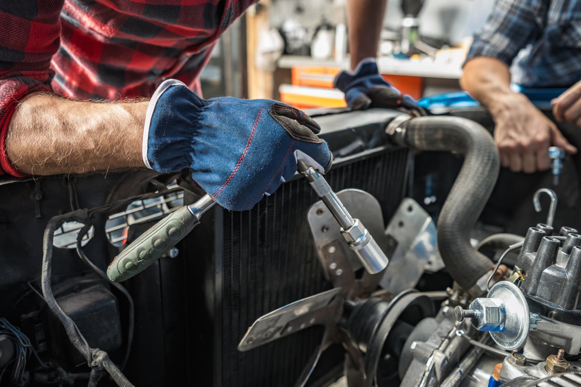 Gloved hands working on a vehicle engine in a workshop