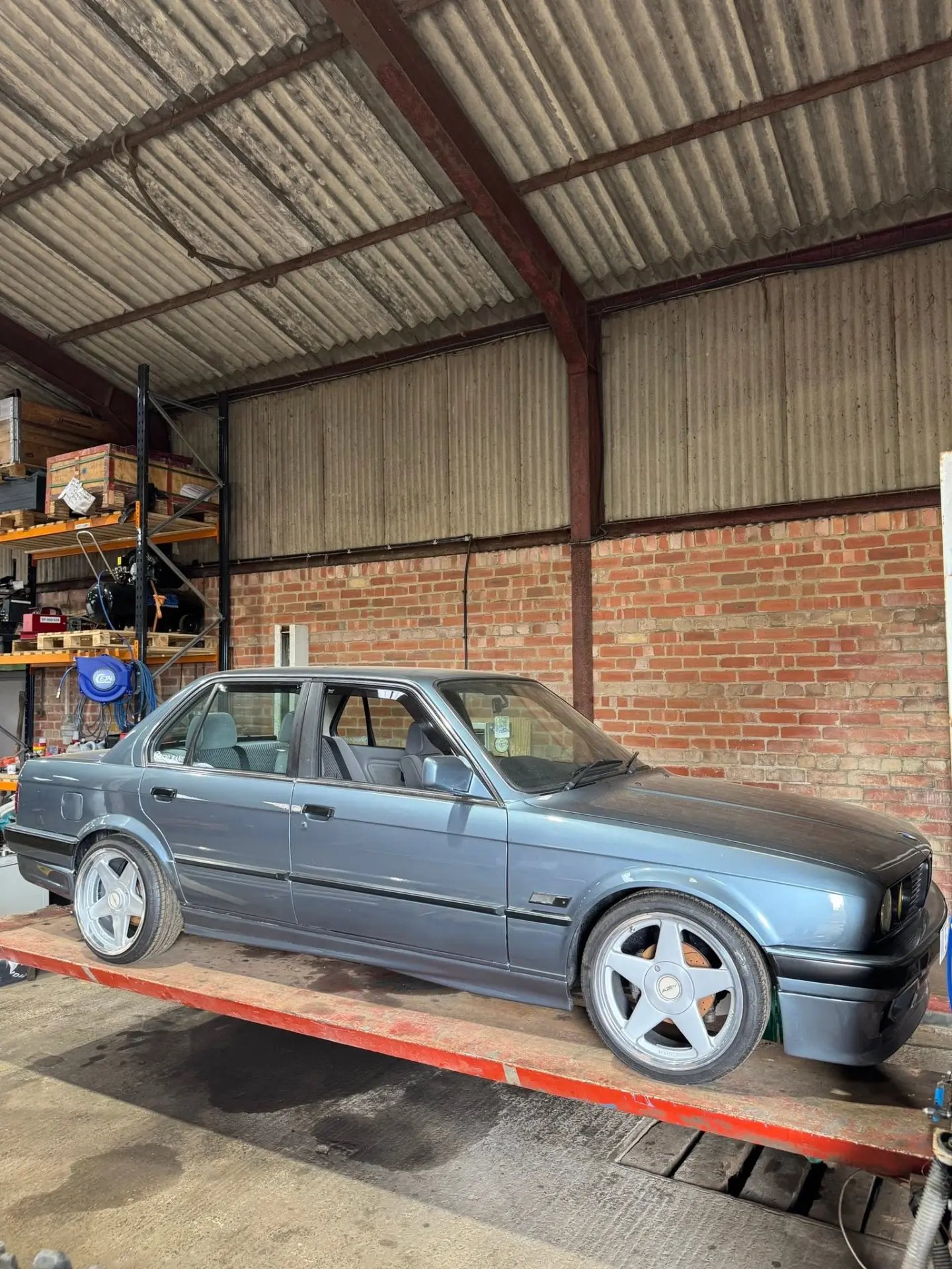Grey BMW E30 saloon on a workshop lift