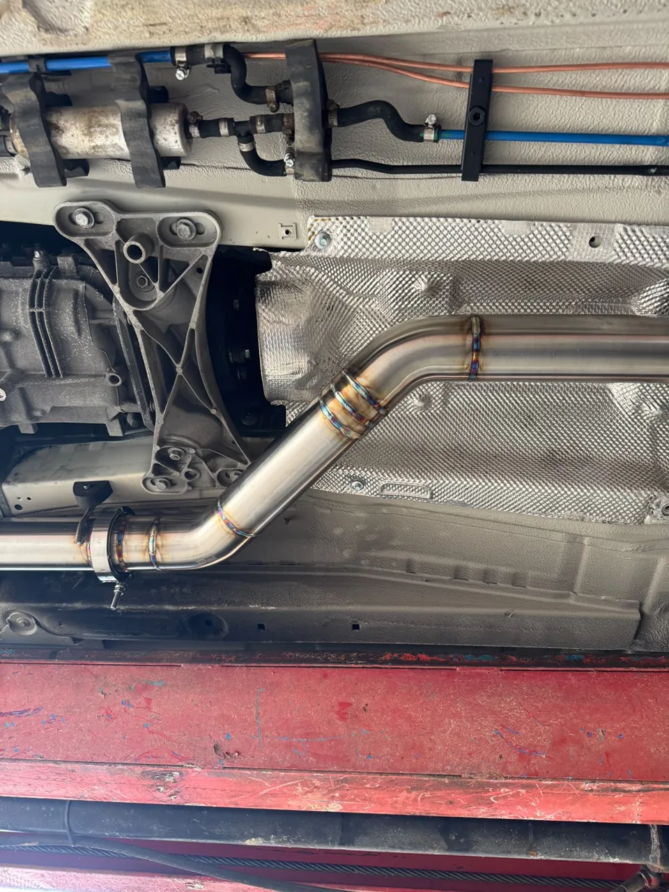 Polished exhaust bend beneath a vehicle floor pan