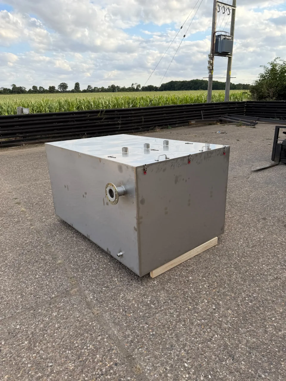 Rectangular stainless fabricated tank outside beside open fields