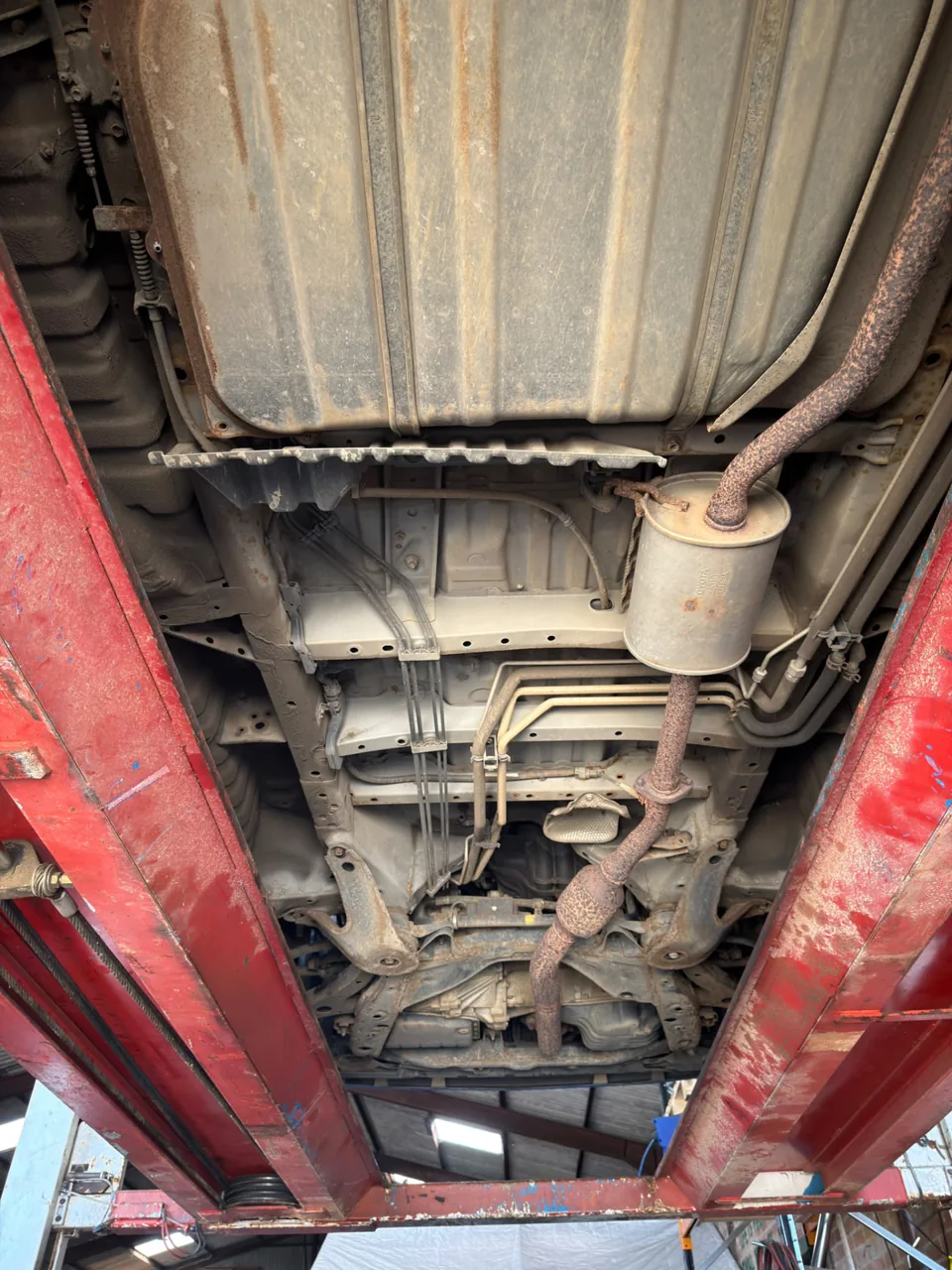 Vehicle fuel tank, exhaust and chassis photographed on a workshop lift