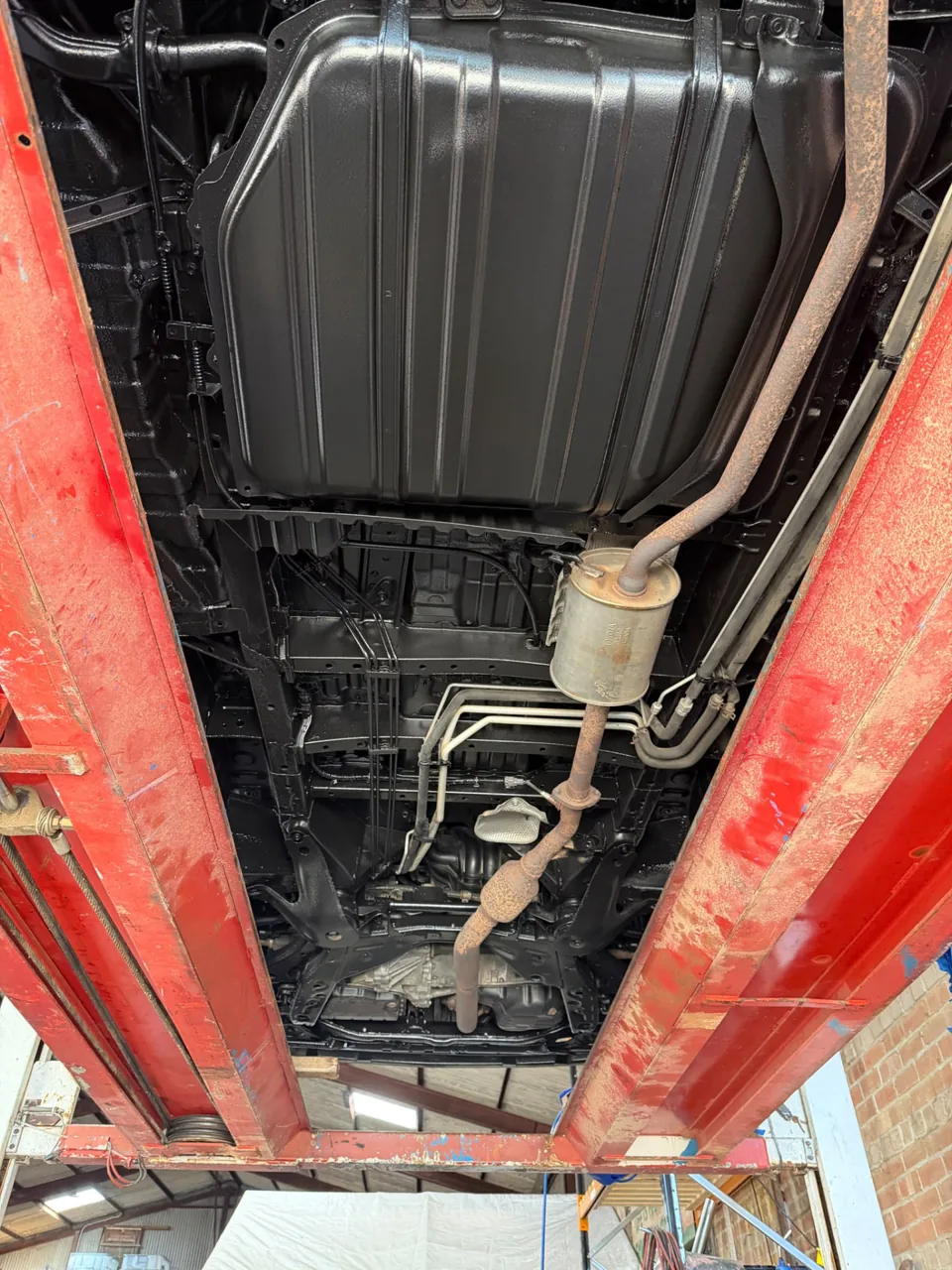 Vehicle underbody showing the fuel tank, exhaust and chassis on a lift