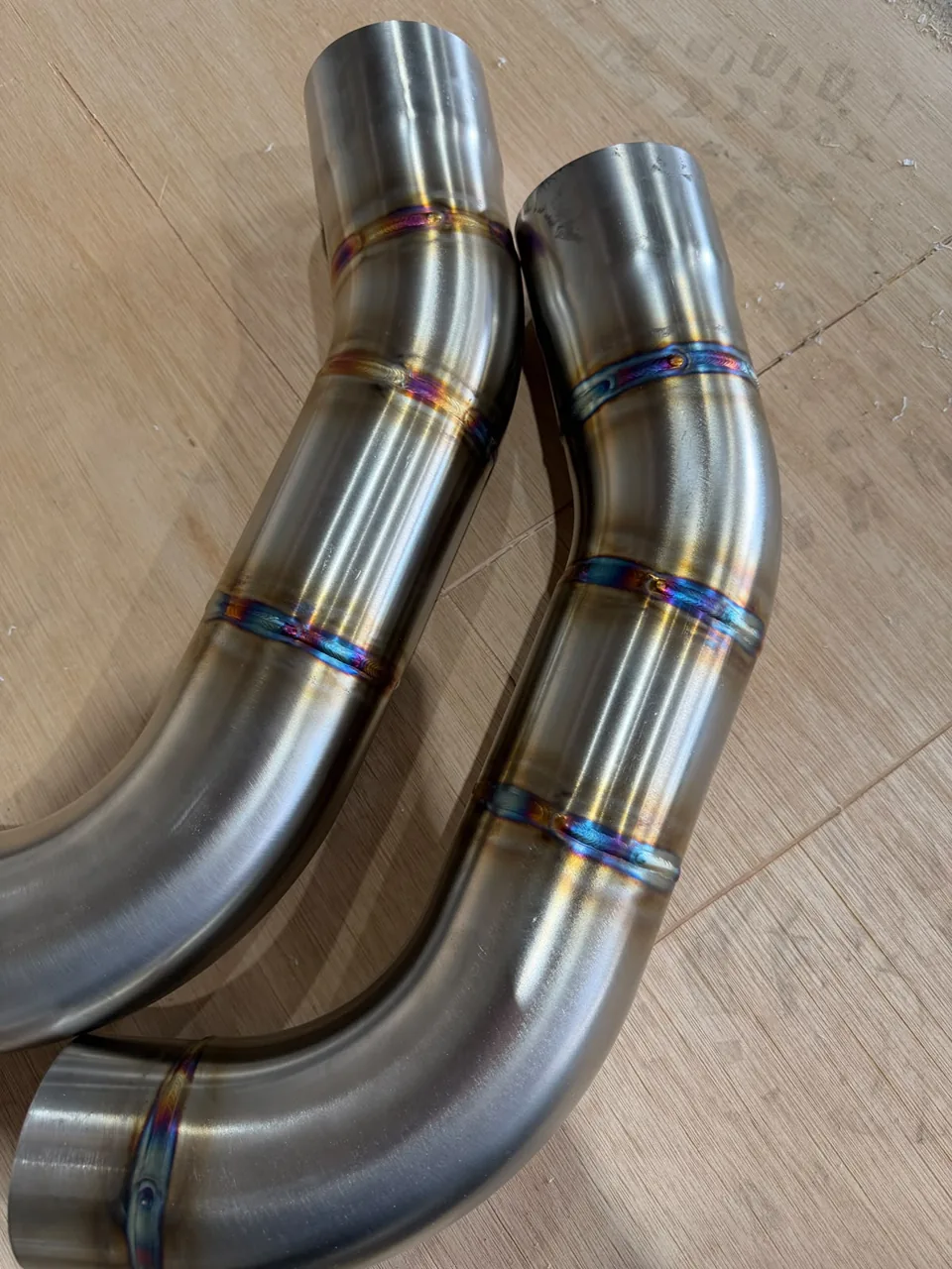 Two curved stainless exhaust sections with heat-tinted welded joints