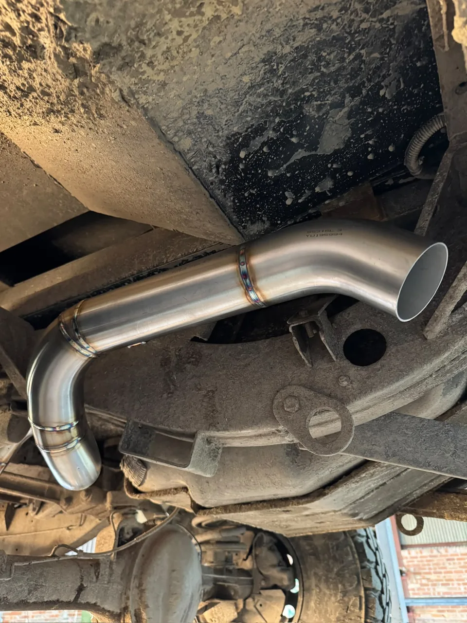 Stainless exhaust tailpipe routed around a vehicle rear suspension