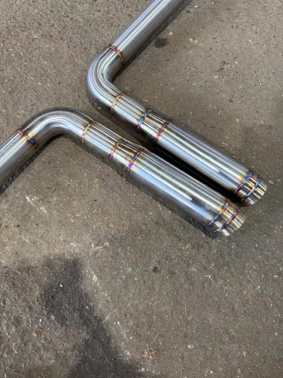 Welded stainless exhaust assembly with twin silencer sections on the workshop floor