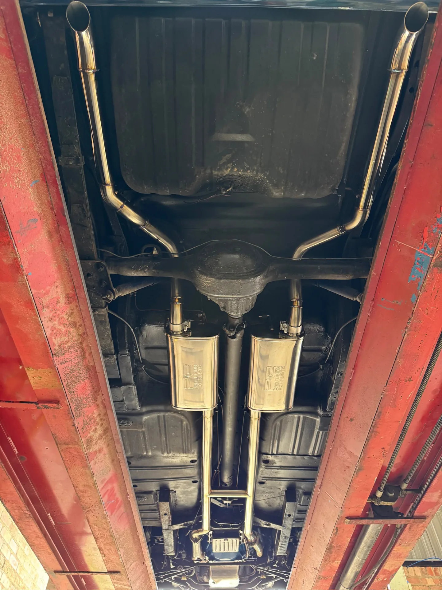 Twin stainless exhaust silencers fitted beneath a vehicle fuel tank