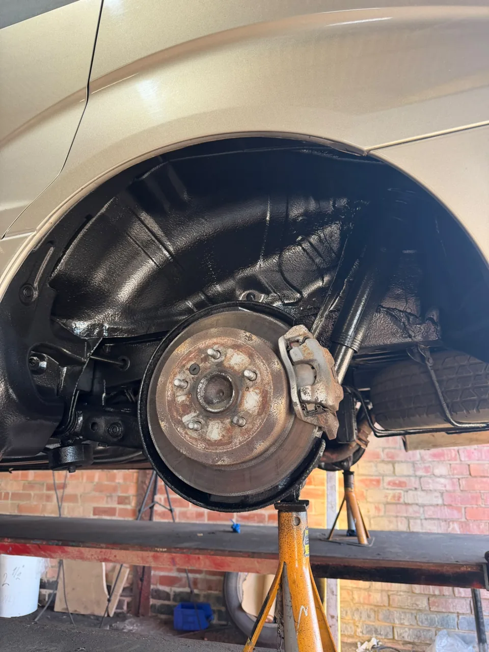 Coated black inner wheel arch with brake disc and suspension exposed